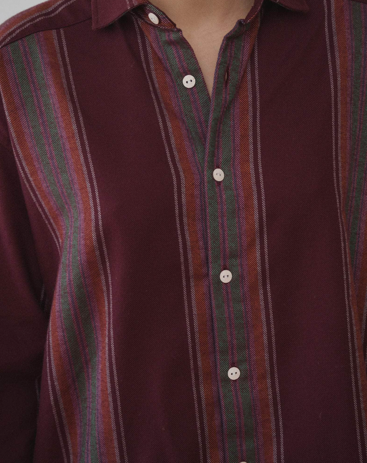 Close-up of a maroon shirt with green and red striped collar and cuffs.