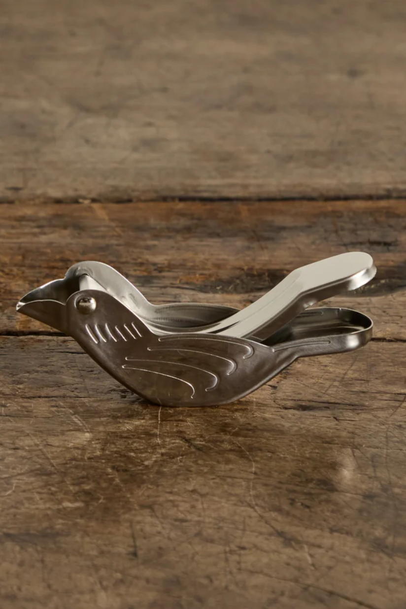 Silver bird-shaped clip on a wooden surface