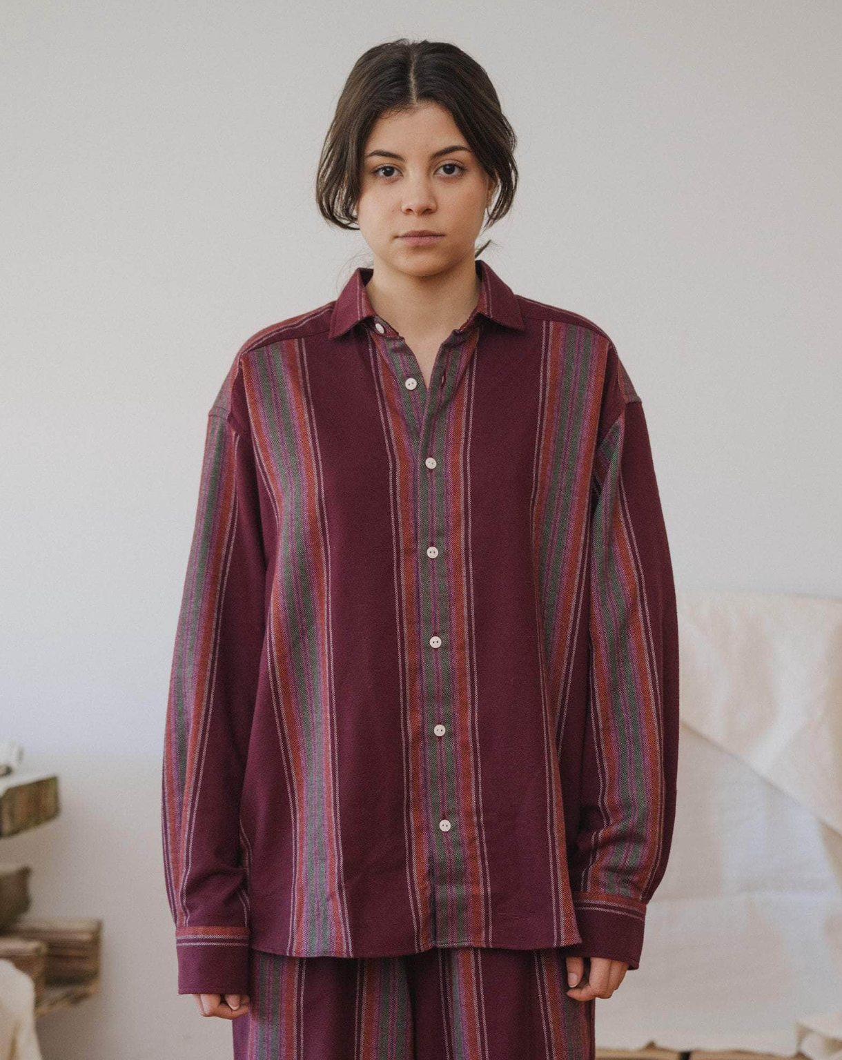 Person wearing a burgundy striped shirt and pants in a minimal indoor setting