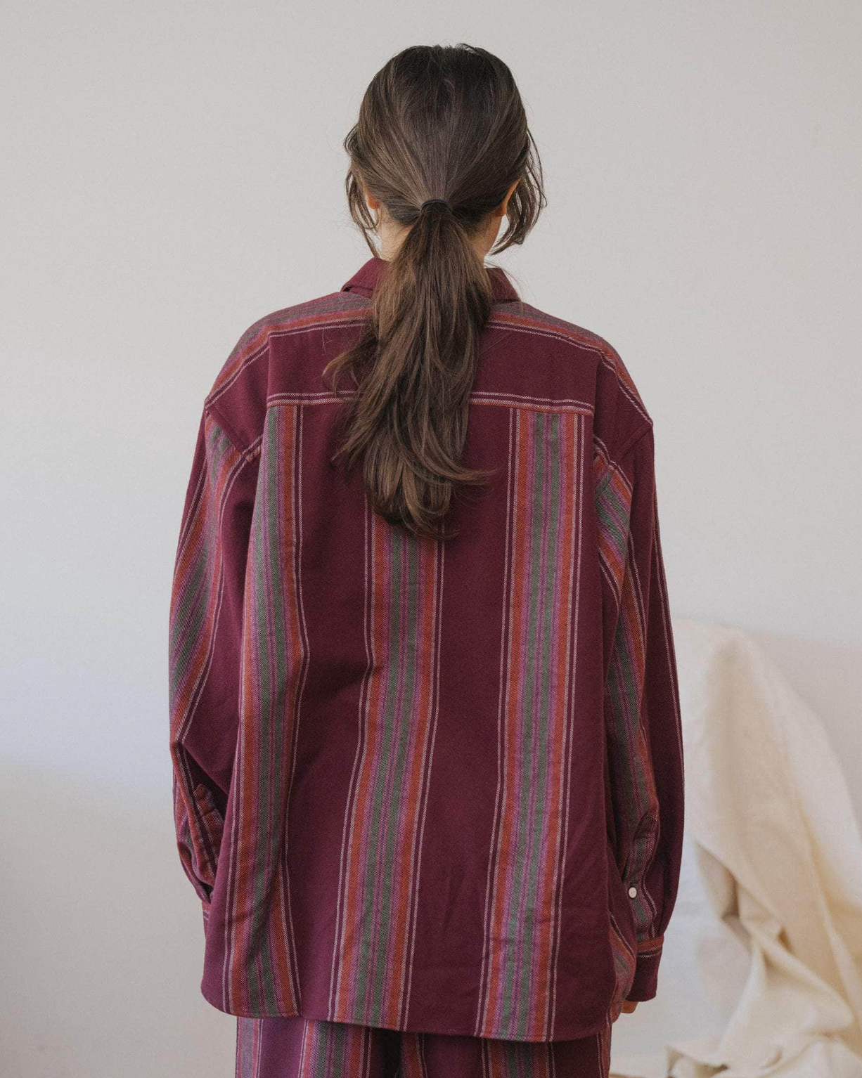 Person wearing a burgundy striped shirt with a plain background