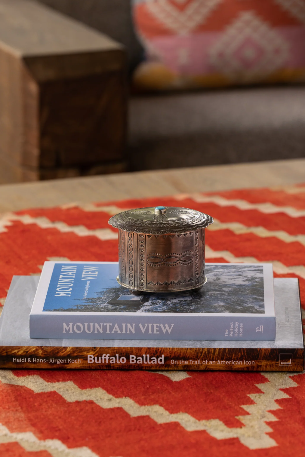 Silver stamped box on a book titled 'Mountain View' on a red and beige patterned surface.