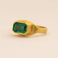 Gold ring with a green gemstone on a beige background